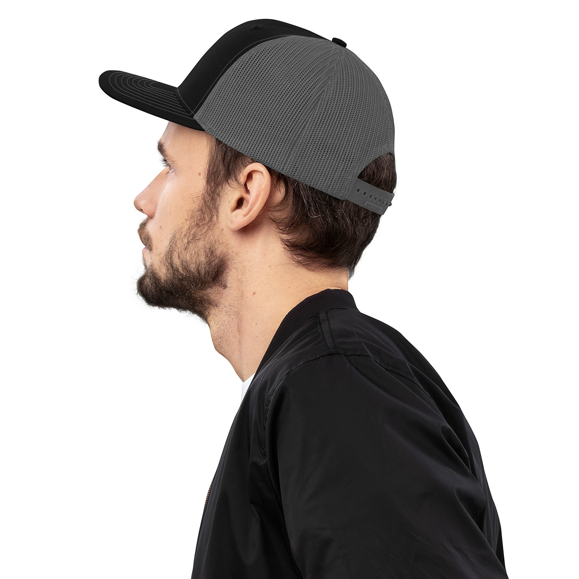 Stylio black and grey trucker cap with mesh back and curved visor, worn by a man.