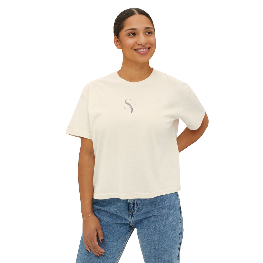 Stylio cream pigment-dyed cotton boxy tee with a subtle grey logo on the chest, worn by a woman with jeans.