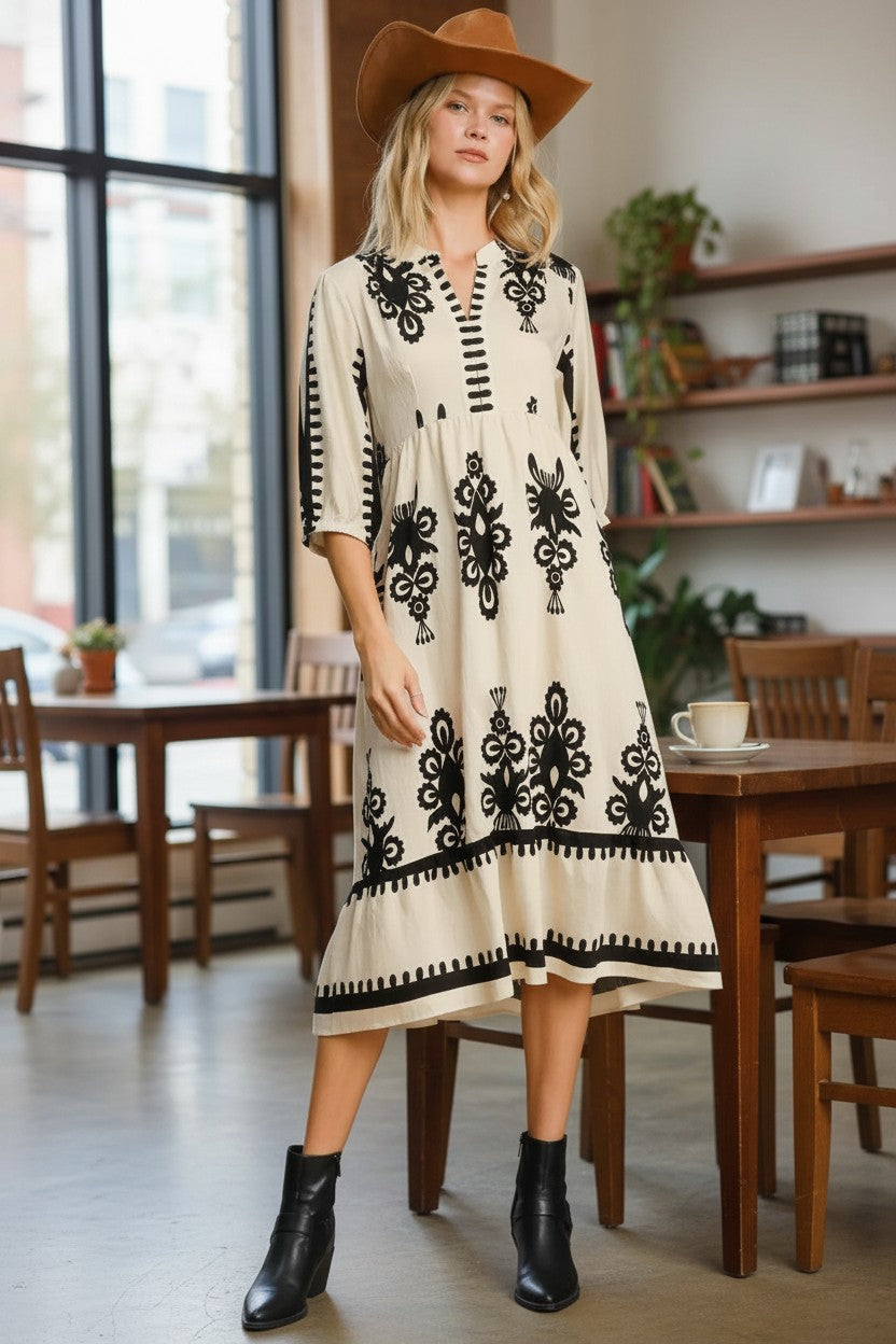 Stylio cream midi dress with black damask print, notched neckline, ruffled hem, and 3/4 sleeves.