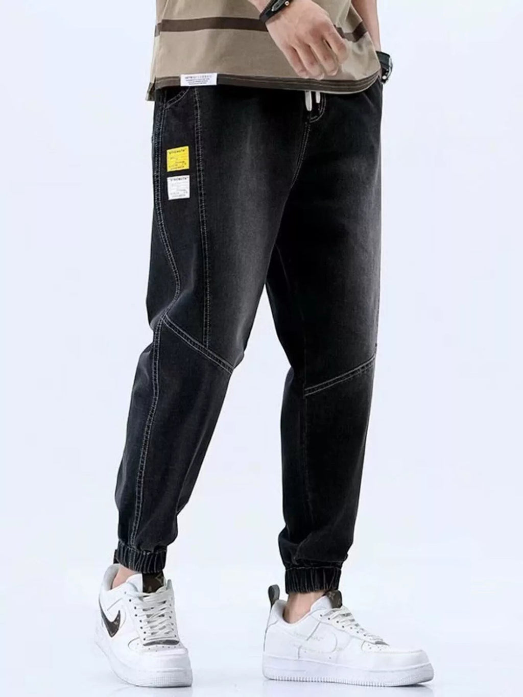 Stylio men's black relaxed fit drawstring jeans with elastic cuffs and white stitching. Made from 100% cotton.