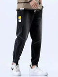 Stylio men's black relaxed fit drawstring jeans with elastic cuffs and white stitching. Made from 100% cotton.