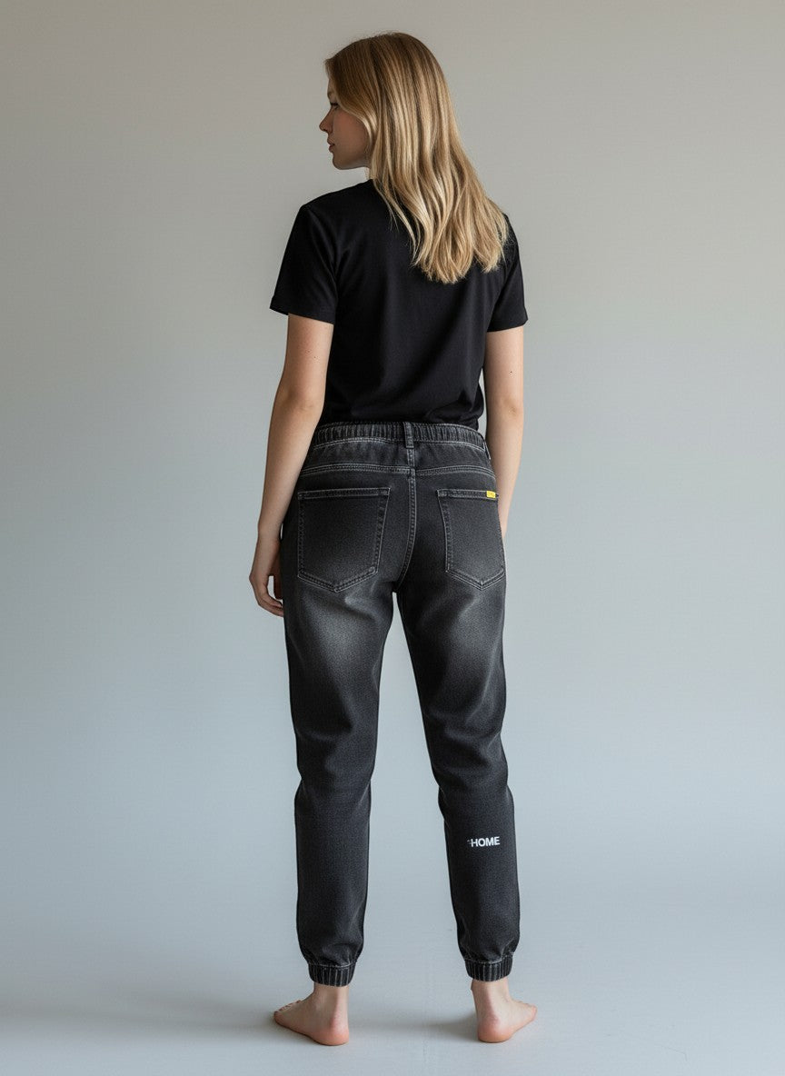 Stylio men's dark grey washed denim jeans with drawstring waist and elastic cuffs, featuring a loose fit and subtle "HOME" embroidery on the left leg.