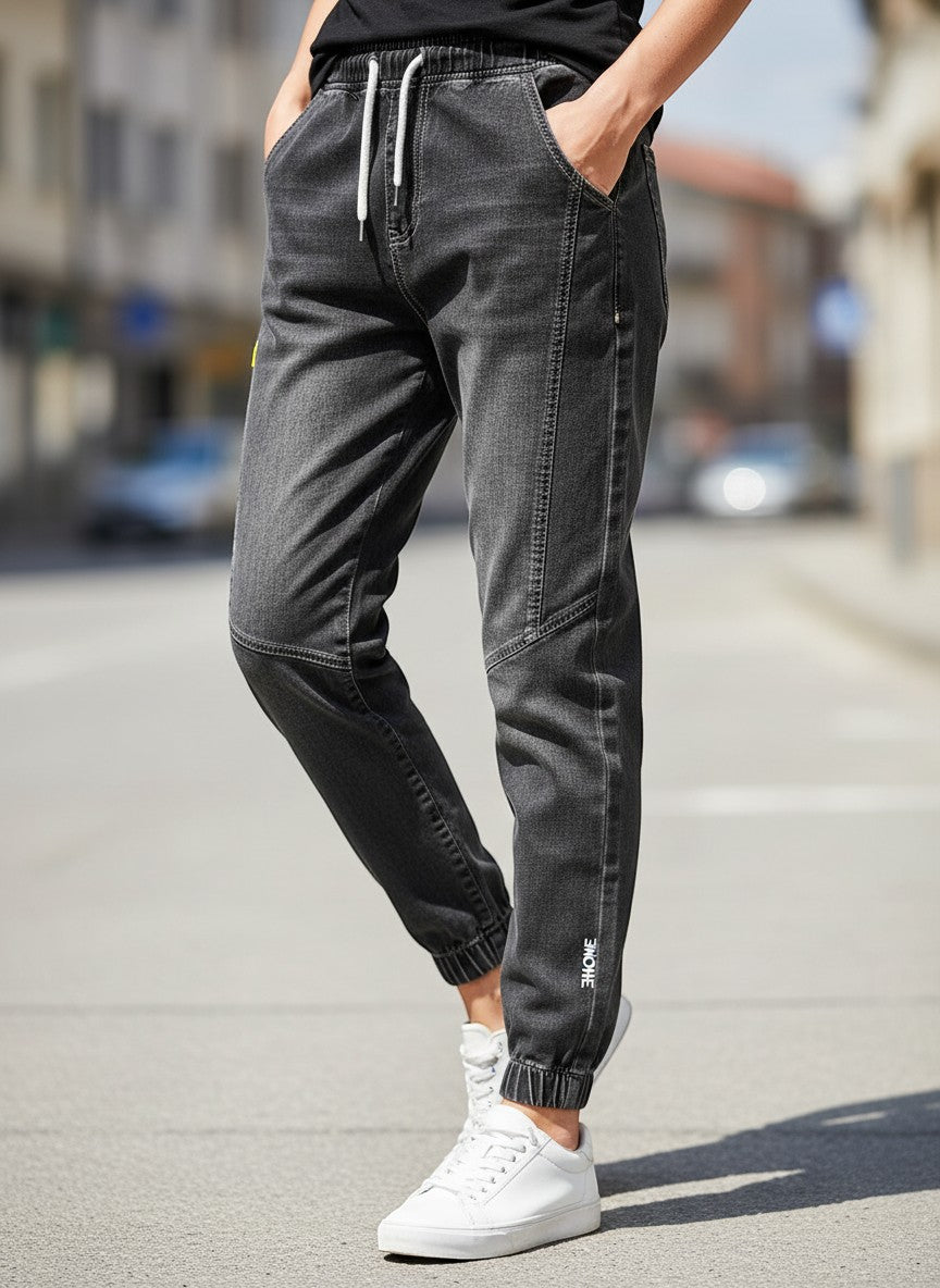 Stylio men's dark grey 100% cotton drawstring jeans with a loose fit and elastic cuffs. Casual style.