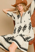 Stylio cream midi dress with black floral print, notched neckline, and ruffled short sleeves. Model wears a brown hat.