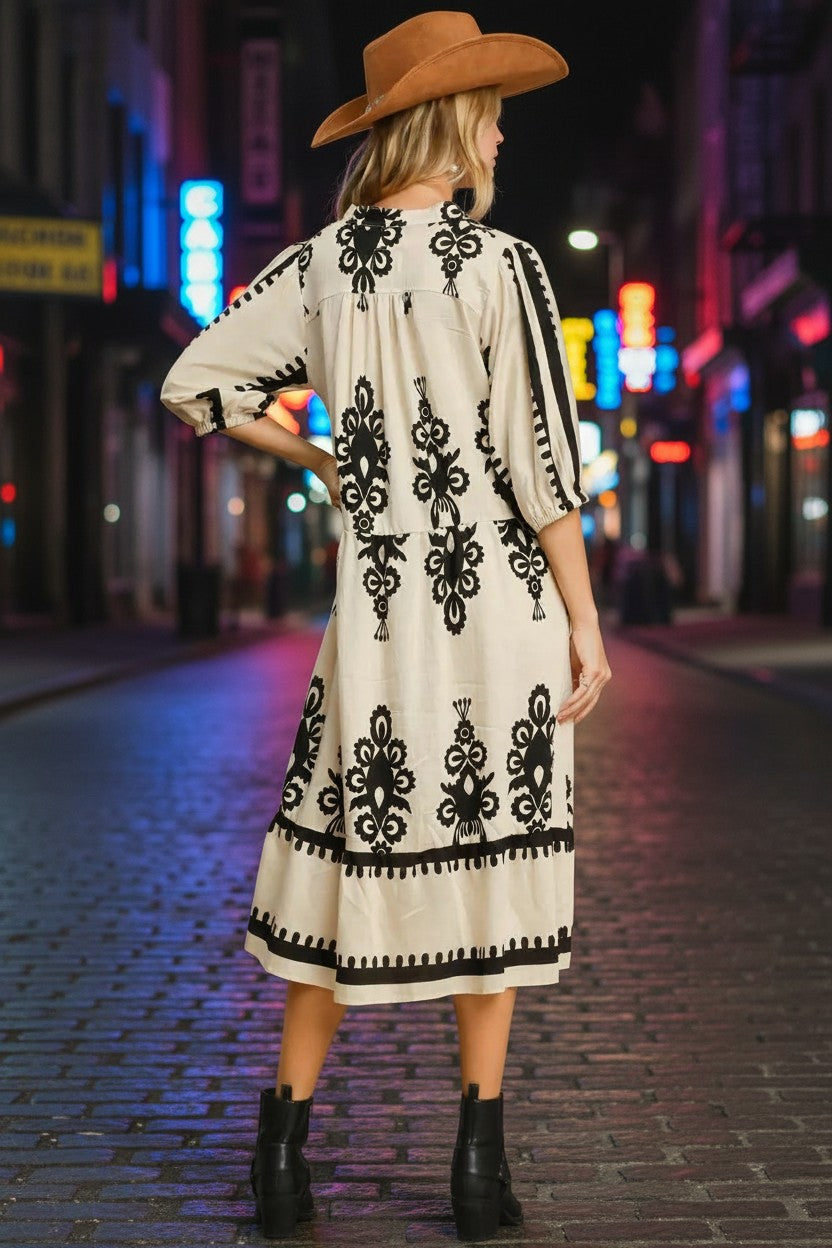 Stylio cream midi dress with black damask print, ruffled hem, and notched neckline. 90% viscose, 10% nylon.