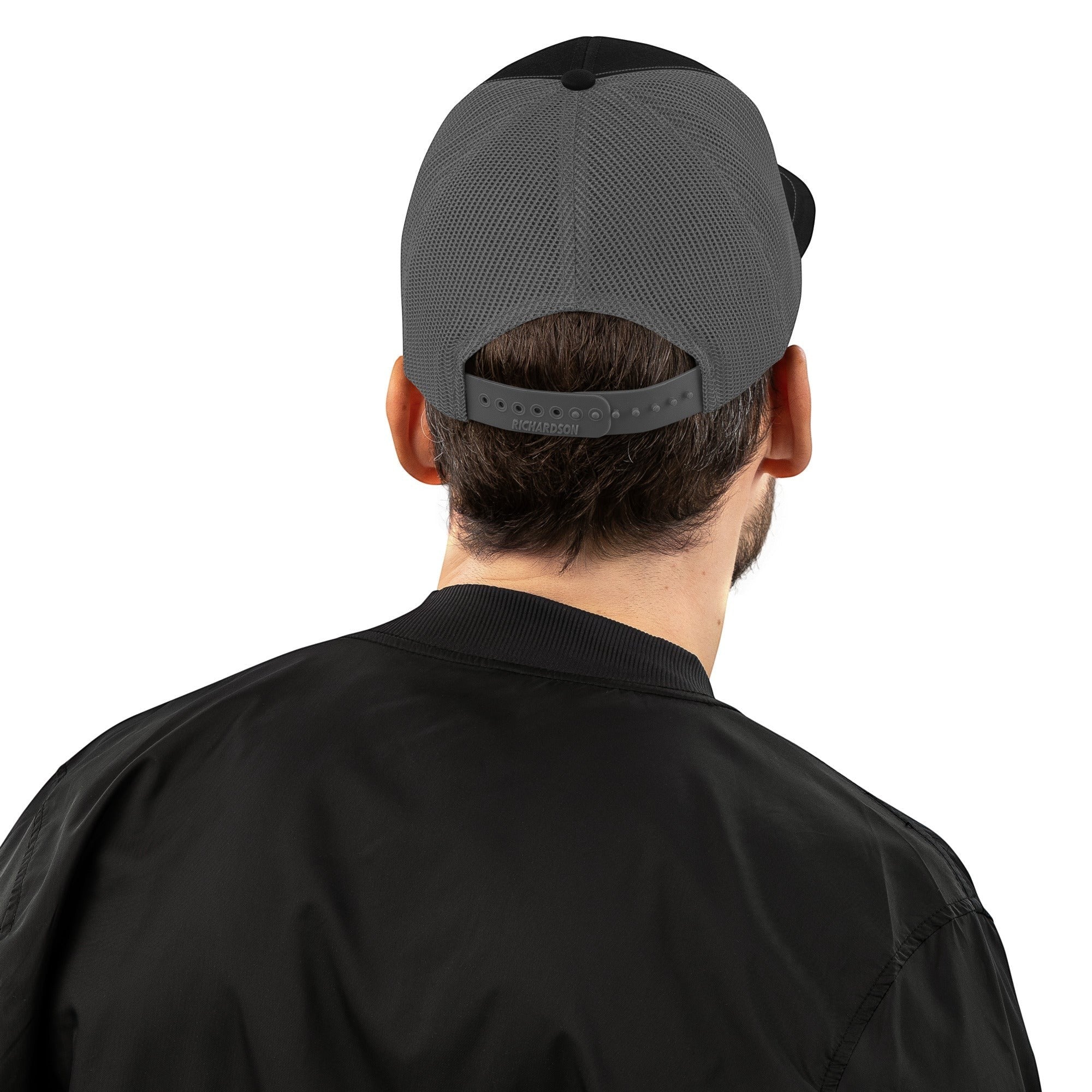 Stylio trucker cap with black front panels and grey mesh back, adjustable snapback closure.