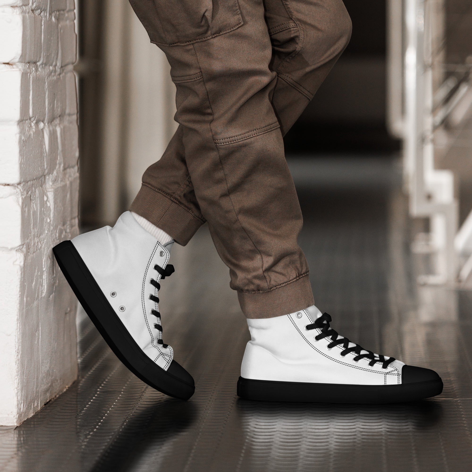 Stylio men's white canvas high top shoes with black laces, soles, and toe caps, worn with brown cargo pants.