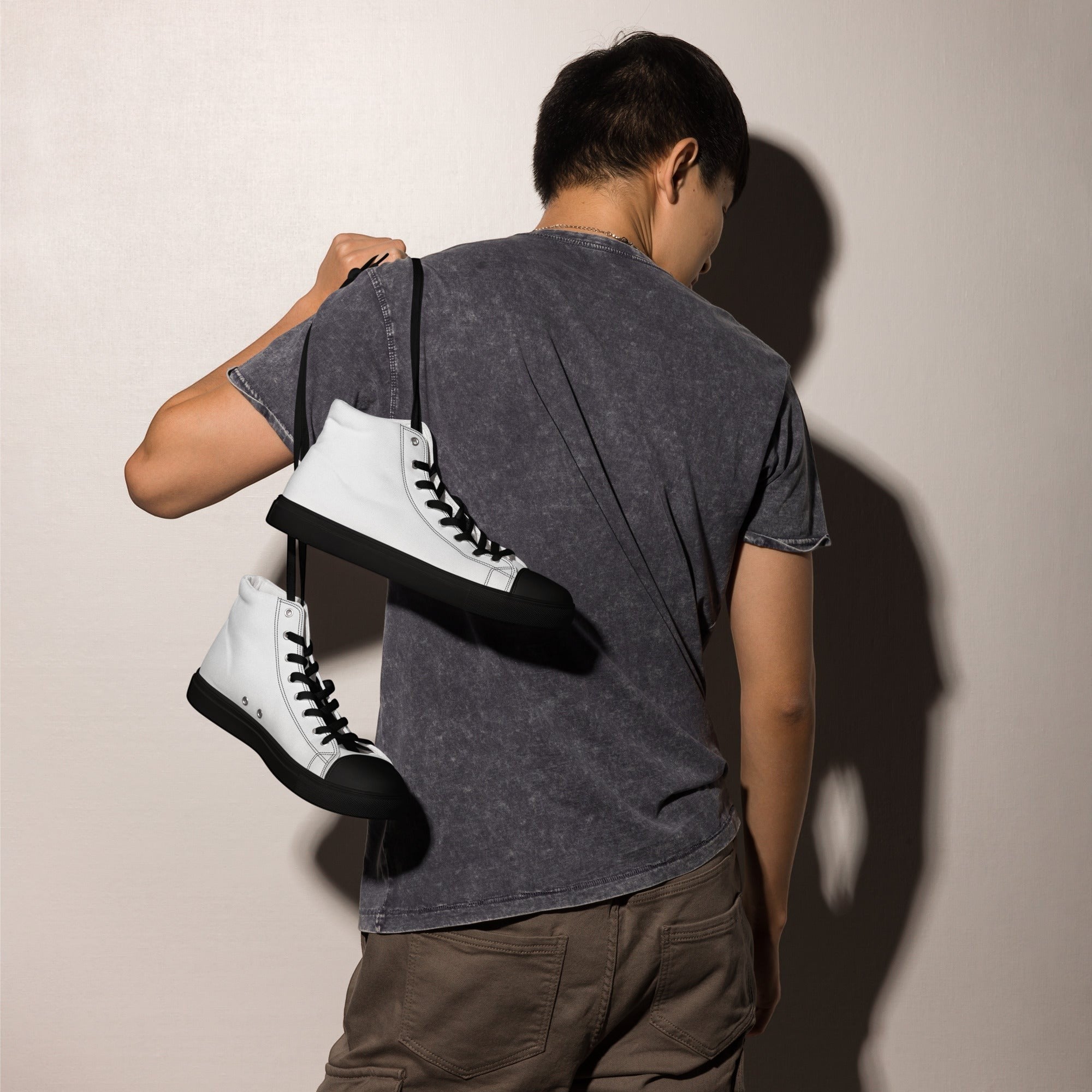Stylio men's white canvas high top sneakers with black laces and soles, worn by a man.