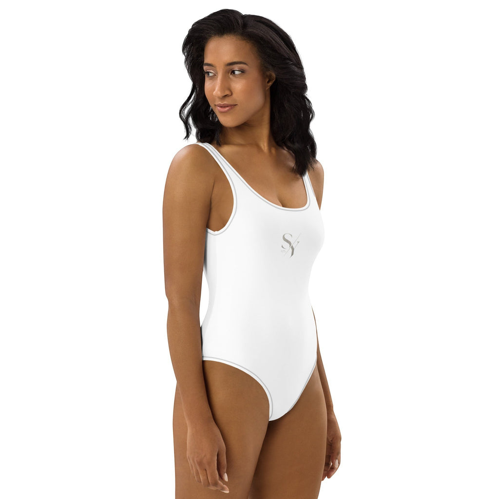 Stylio white one-piece swimsuit with scoop neckline, low scoop back, and subtle grey piping. Made from recycled polyester and elastane.