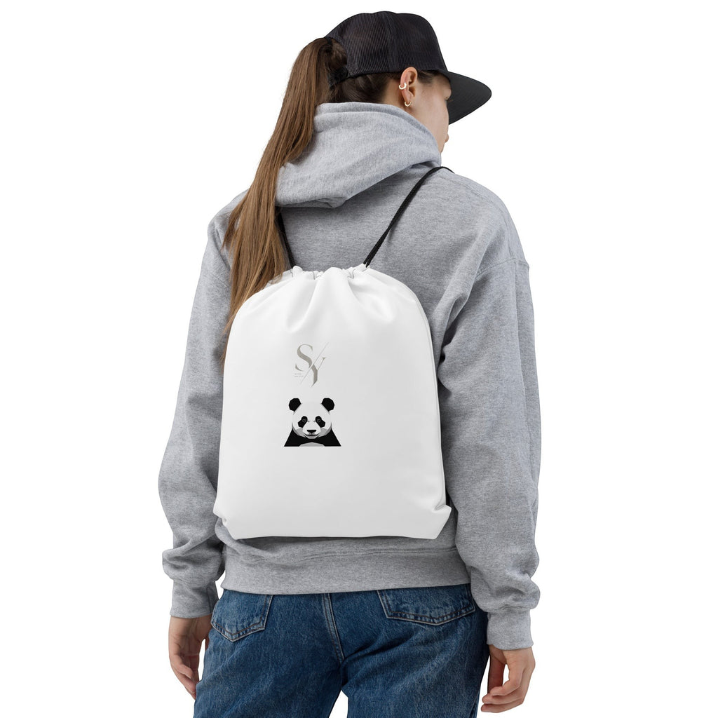 Stylio white polyester drawstring bag with a black panda graphic and logo, worn by a person with a grey hoodie and jeans.
